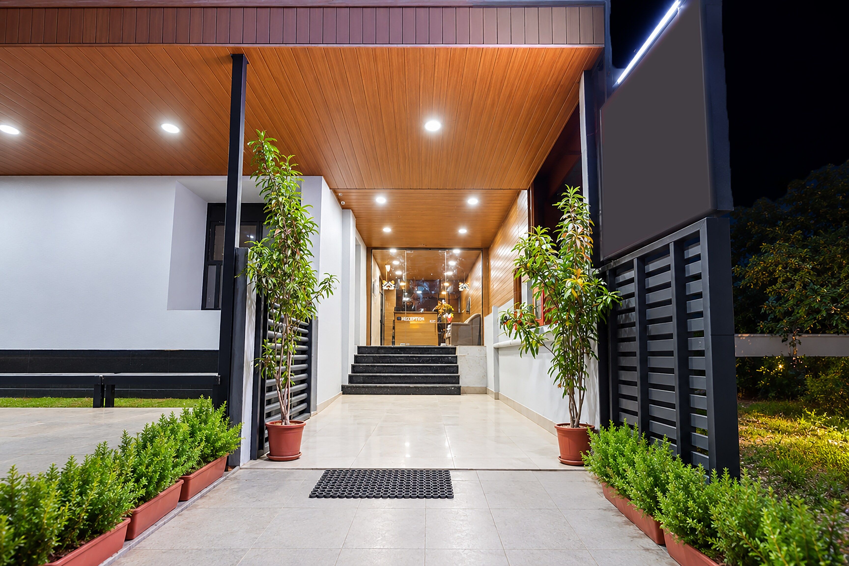 Une entrée moderne avec un plafond en bois, des plantes en pot et un comptoir d’accueil.