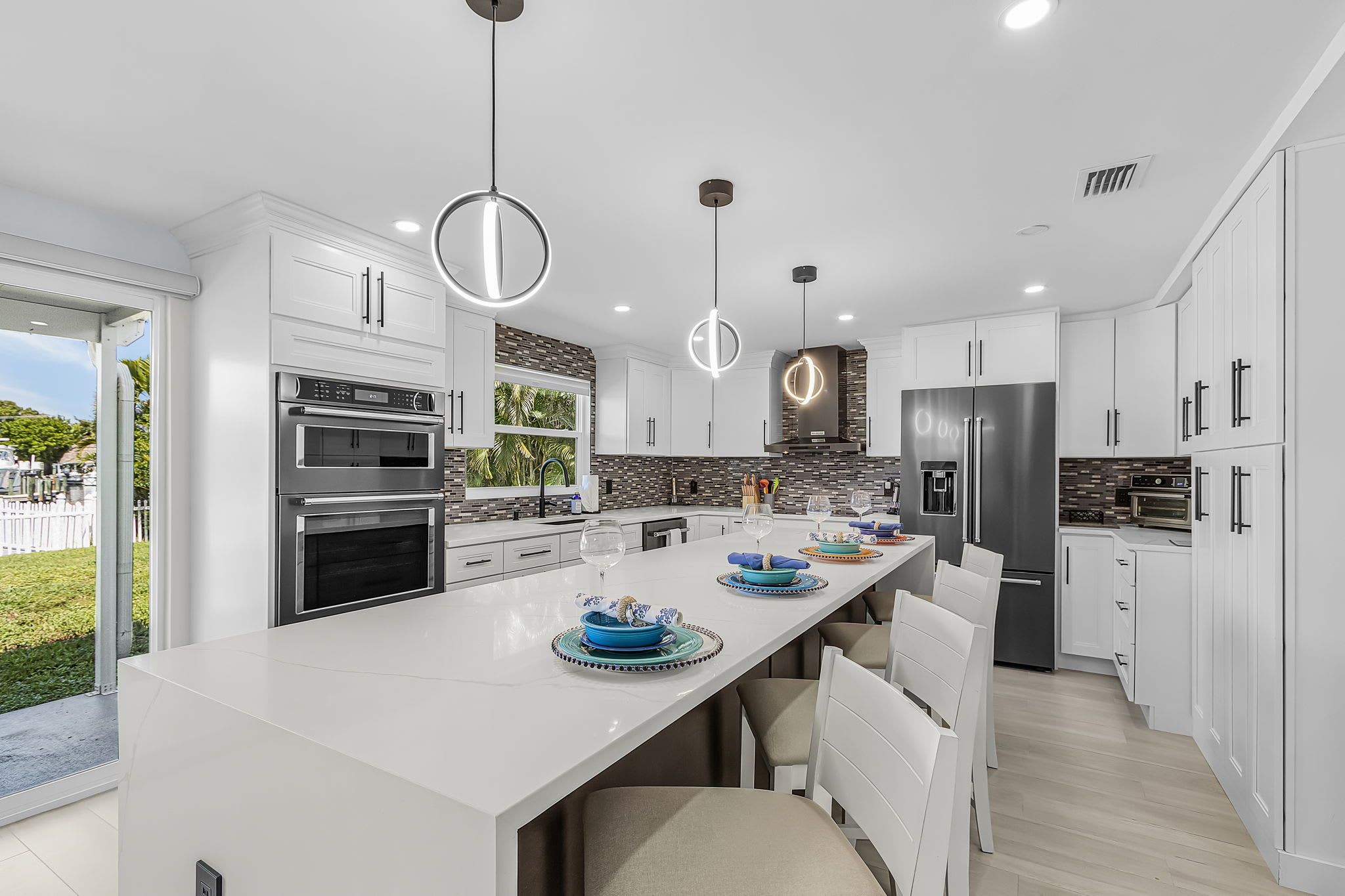 A modern kitchen with white cabinetry, stainless steel appliances, and a central island with seating.