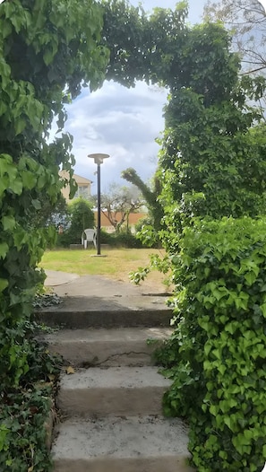 A pathway leading to a house with a chair and a lamp post.