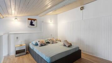 Een slaapkamer met een bed, nachtkastjes, een wandlamp en een plafondventilator.
