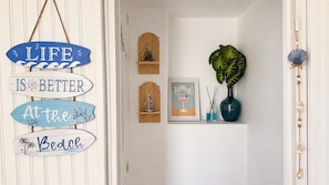 A hallway with a life sign, framed artwork, a potted plant, and decorative items.