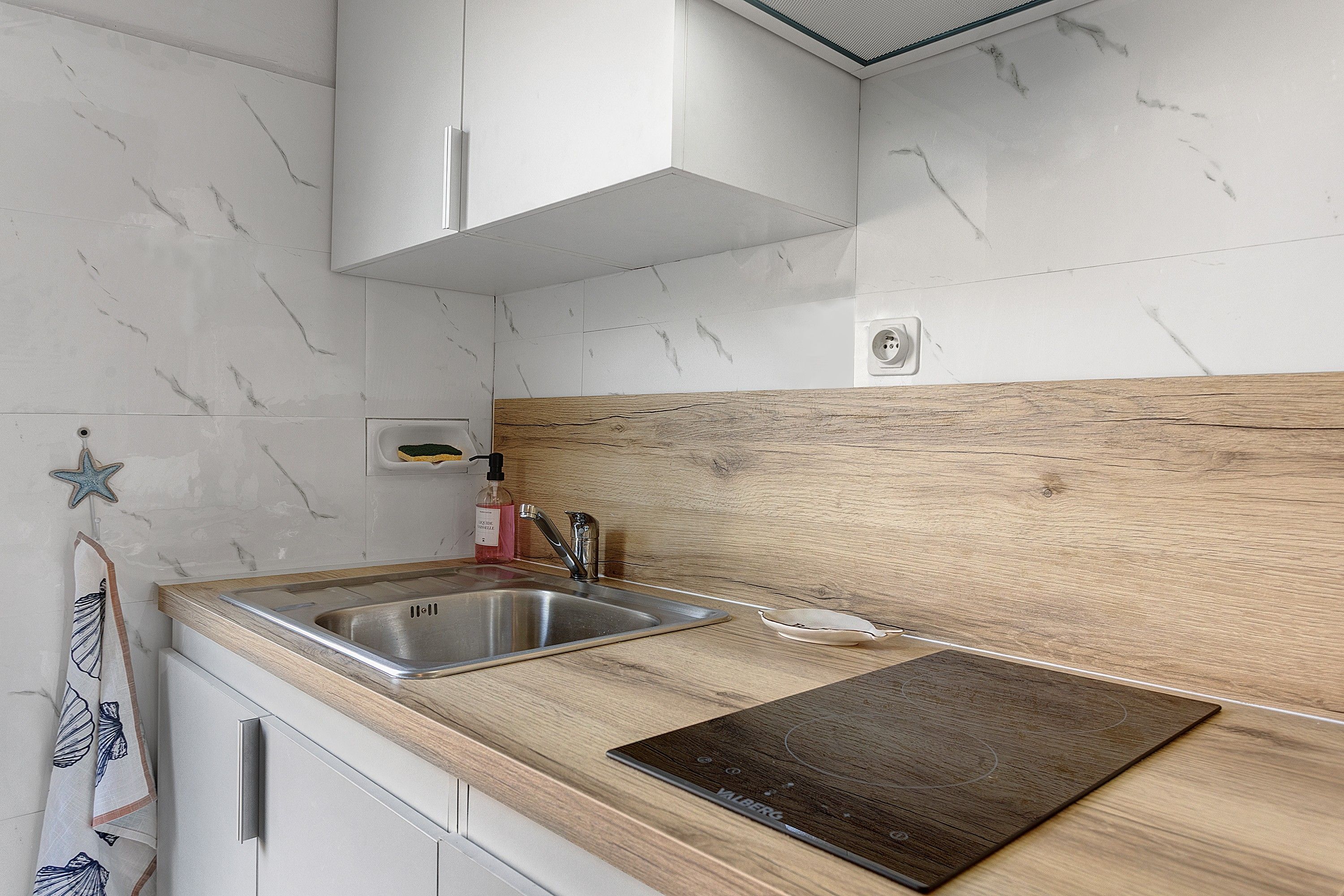 Eine Küche mit Holzarbeitsplatte, Spüle aus Edelstahl und einer Holzrückwand.