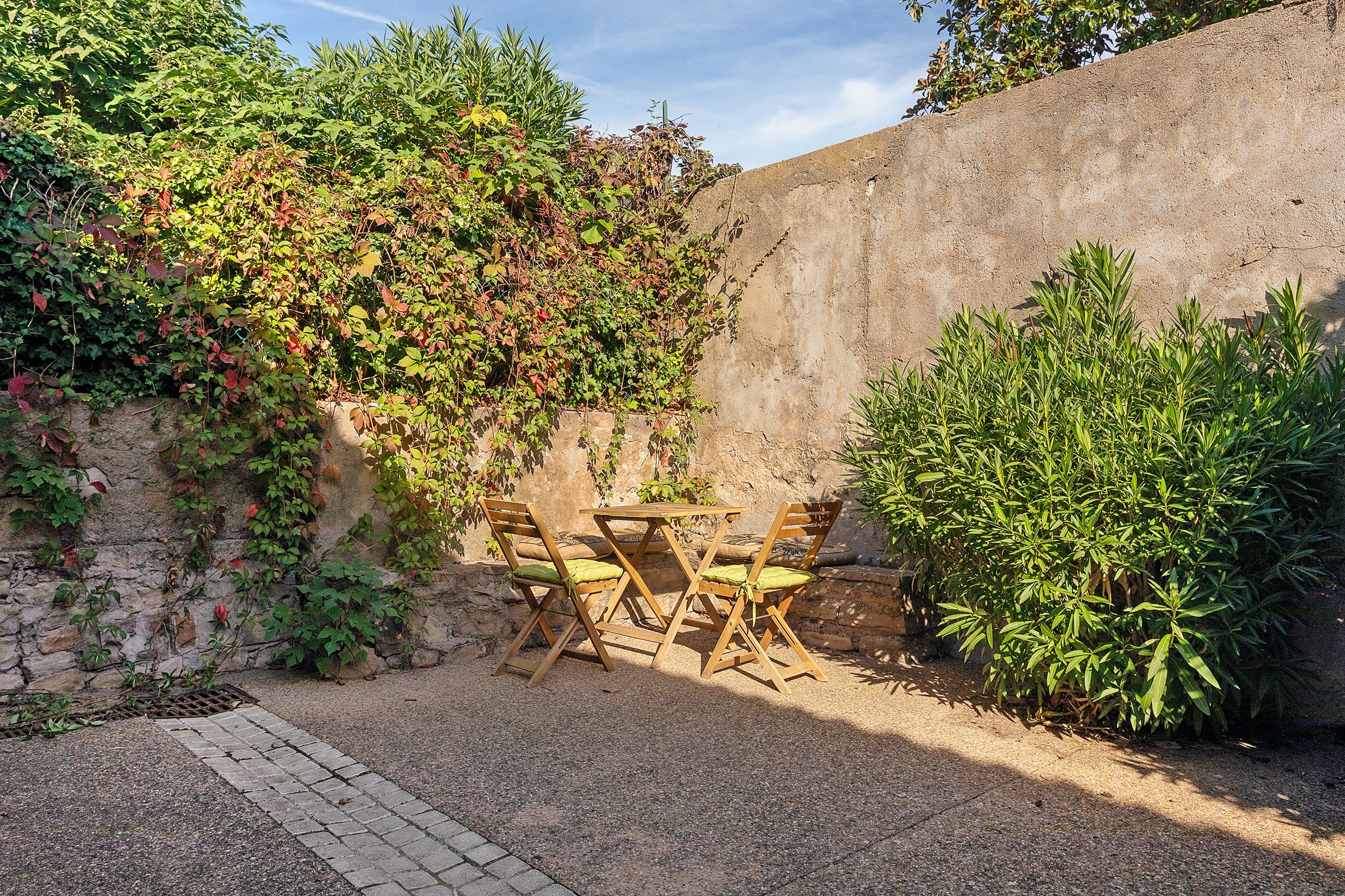 Een terras met een stenen muur, een tafel en stoelen.
