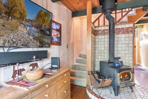 Una camera accogliente con arredamento in legno, un caminetto, una televisione e un quadro che raffigura un paesaggio fluviale.