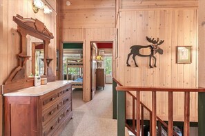 Un interno in legno con un comò, uno specchio e una decorazione a forma di alce appesa al muro.