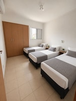 Un dormitorio con dos camas, un armario, una ventana y una lámpara en el techo.