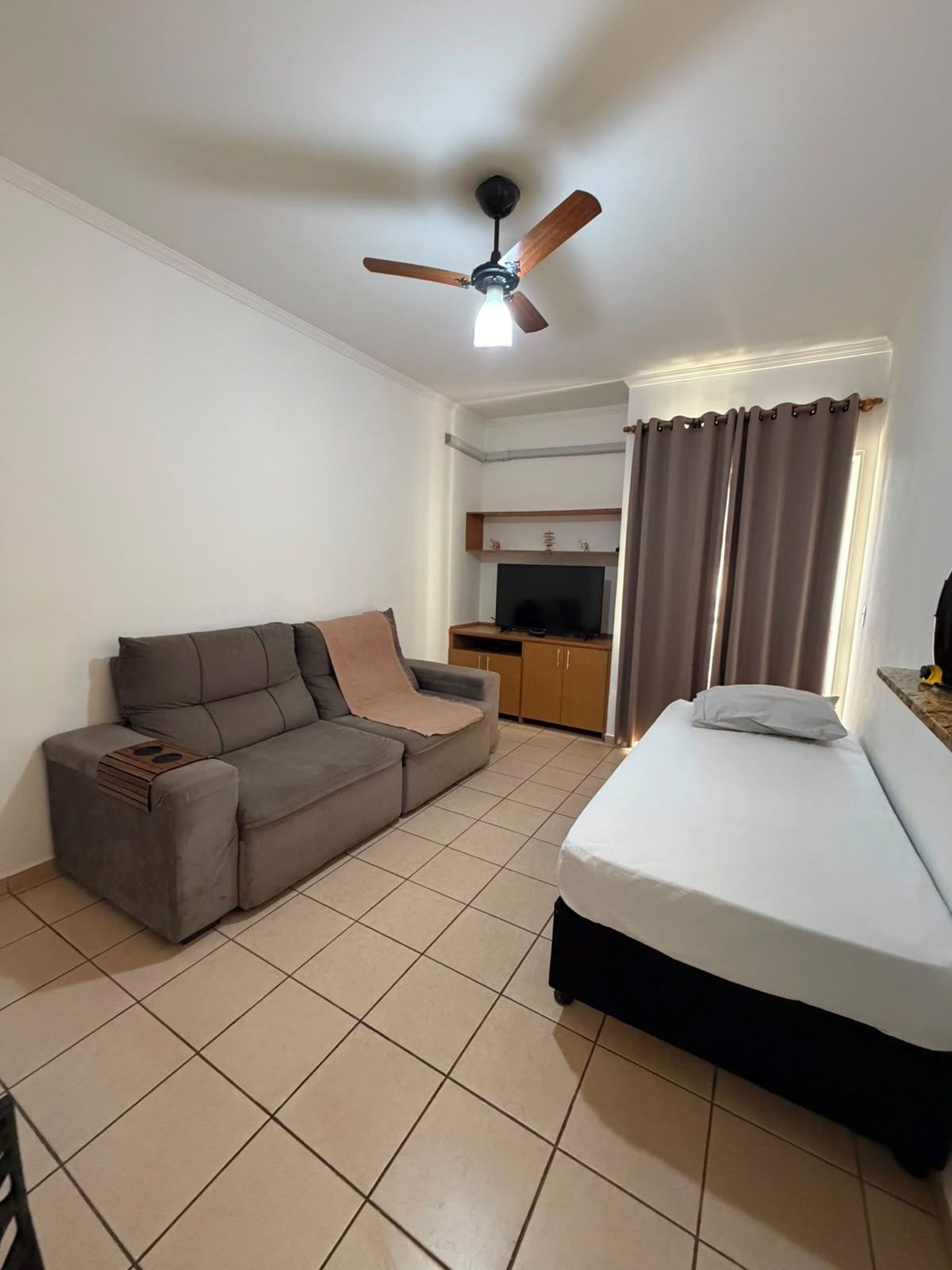 Une pièce comprenant un lit, un canapé, une télévision et un ventilateur de plafond.