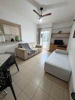Un espacio habitable compacto con kitchenette, un sofá, una cama y un televisor.