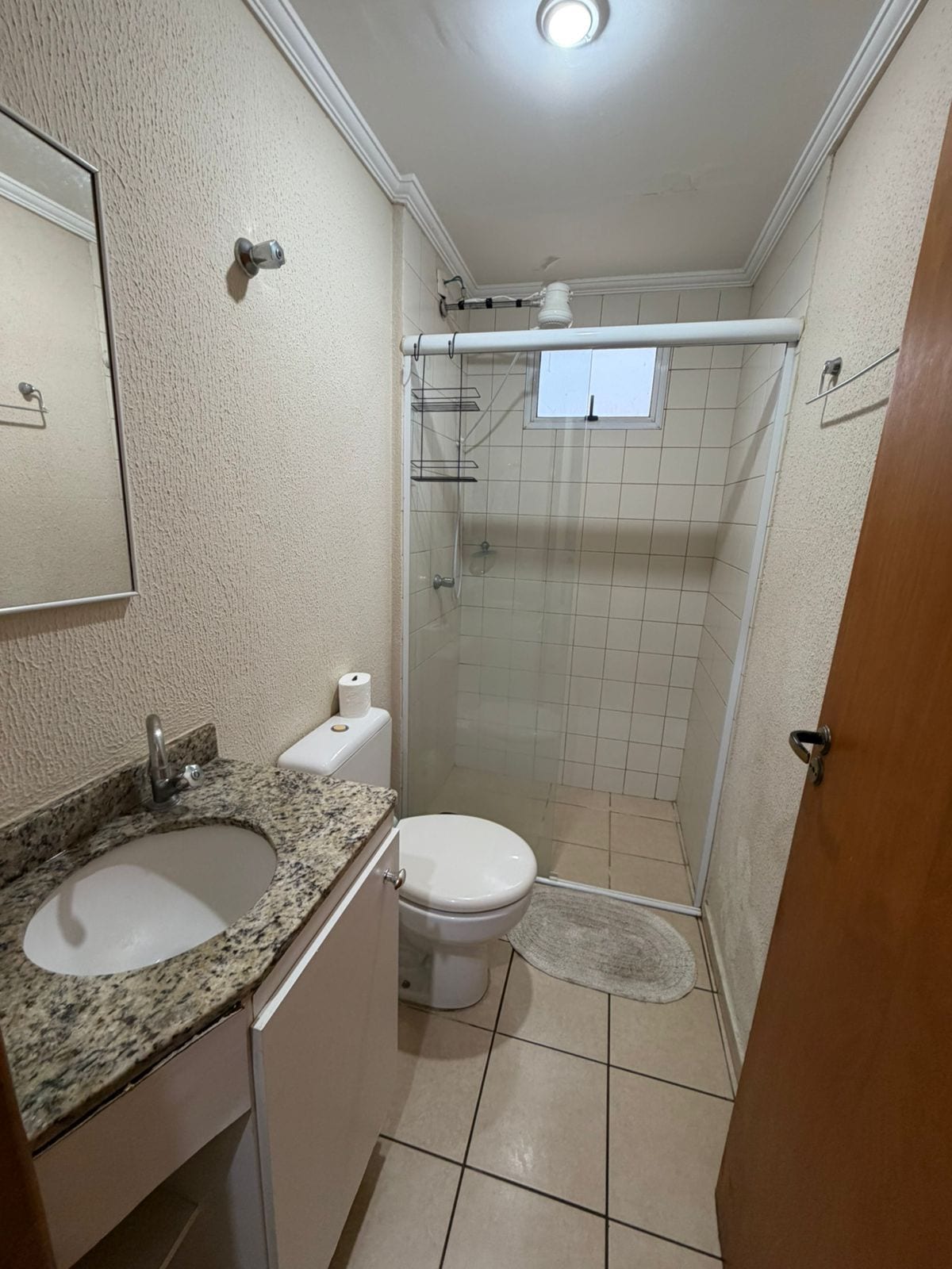 Ein Badezimmer mit Granitwaschtisch, Toilette, Duschkabine aus Glas und einer Tür.