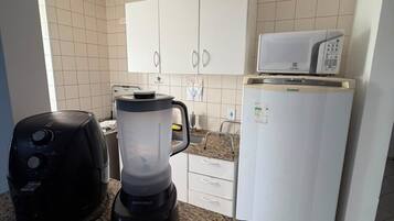 Eine Küche mit Mikrowelle, Toaster, Mixer und Kaffeemaschine auf der Arbeitsplatte.