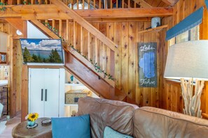 Een houten interieur met een trap, een bank, een tafel met een vaas en een muur met een 'Lake Tahoe' bord.