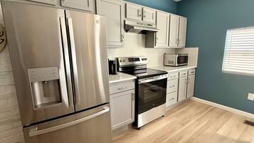 A modern kitchen with stainless steel appliances, white cabinetry, and a blue accent wall.