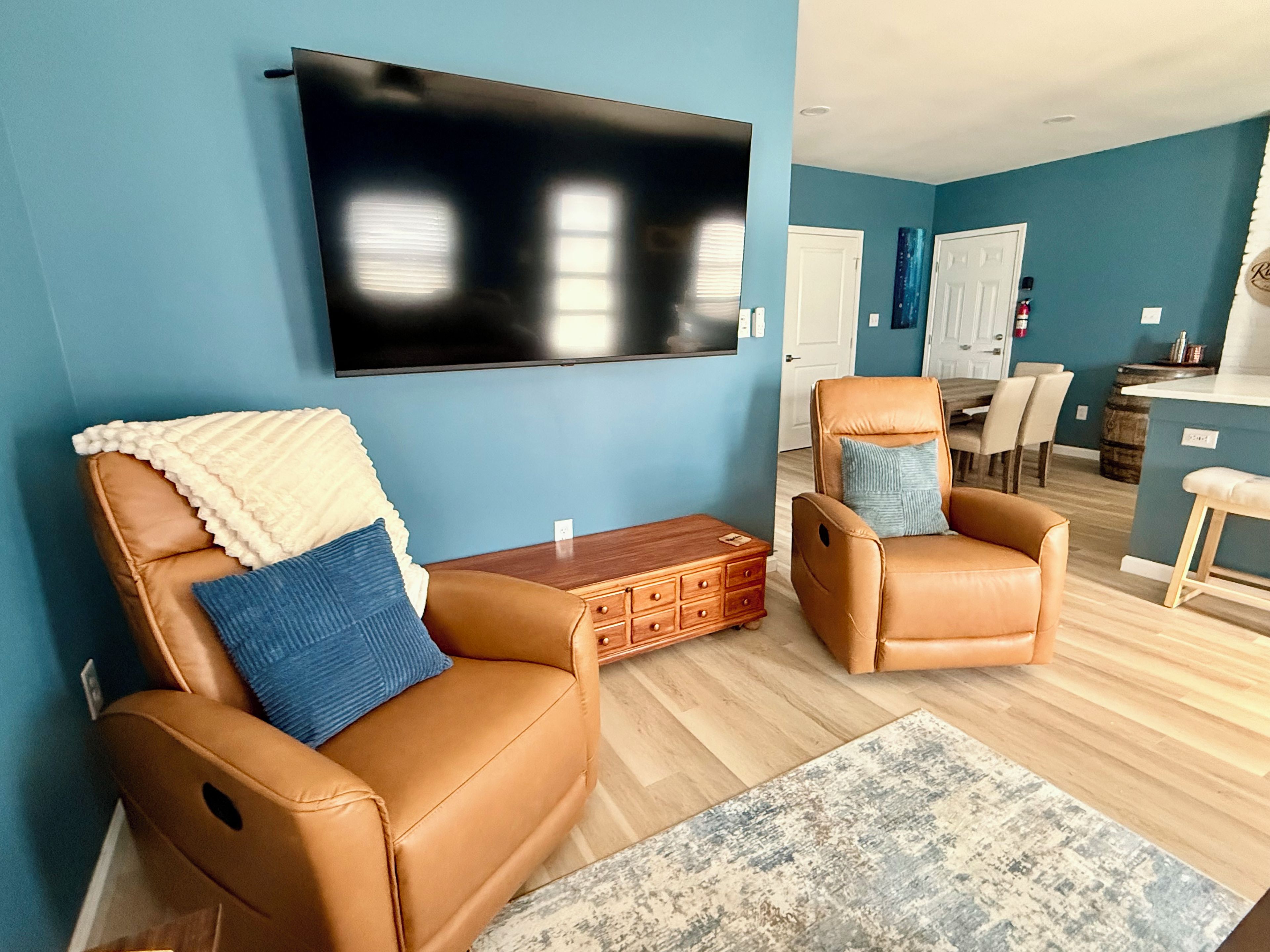 Una sala de estar con dos sillones de cuero, un televisor de pantalla plana y una mesa de centro de madera.