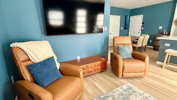 Una sala de estar con dos sillones de cuero, un televisor de pantalla plana y una mesa de centro de madera.