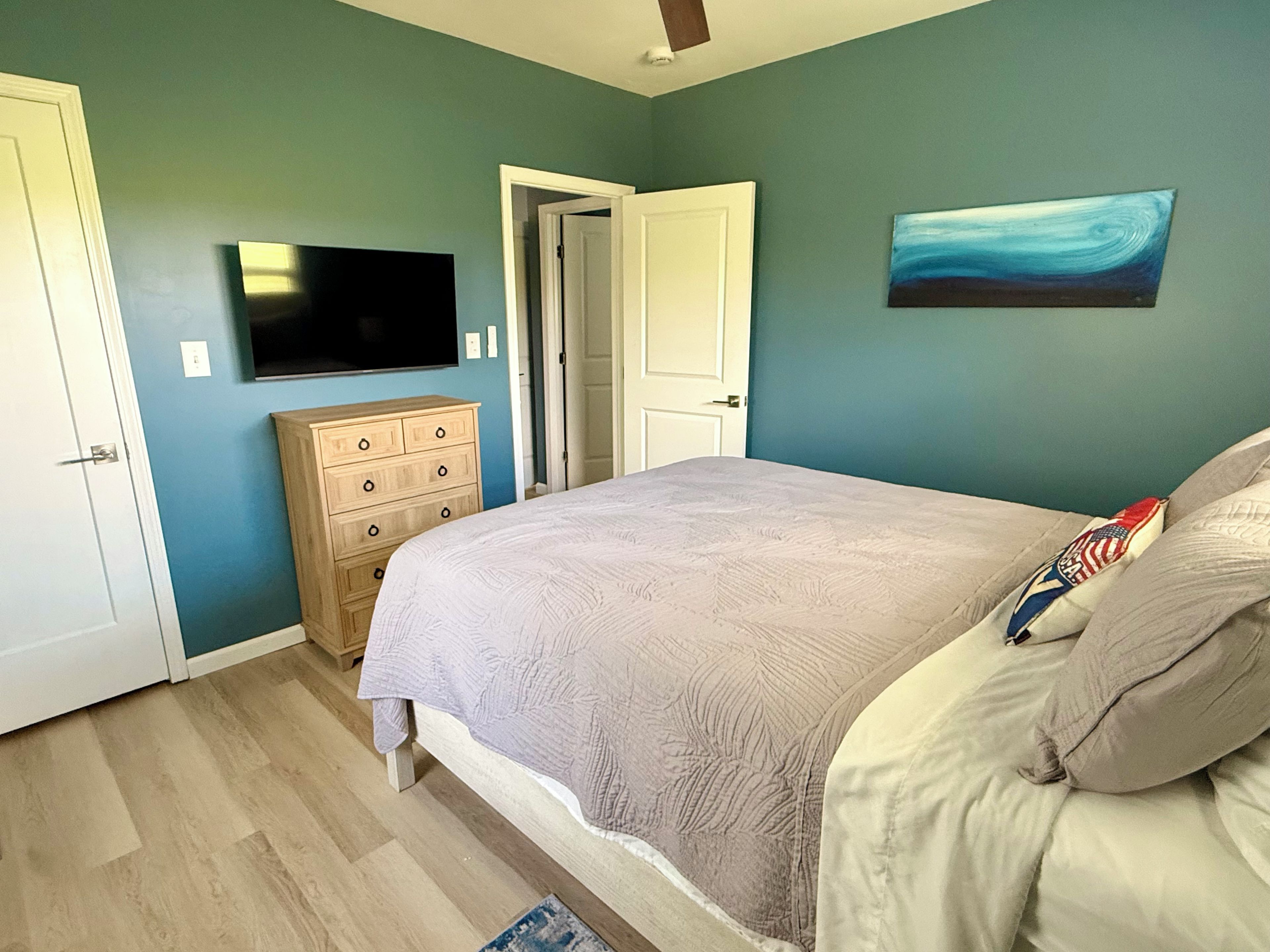Ein Schlafzimmer mit Bett, Schminktisch, Fernseher und Bildern an der Wand.