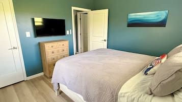 Ein Schlafzimmer mit Bett, Schminktisch, Fernseher und Bildern an der Wand.