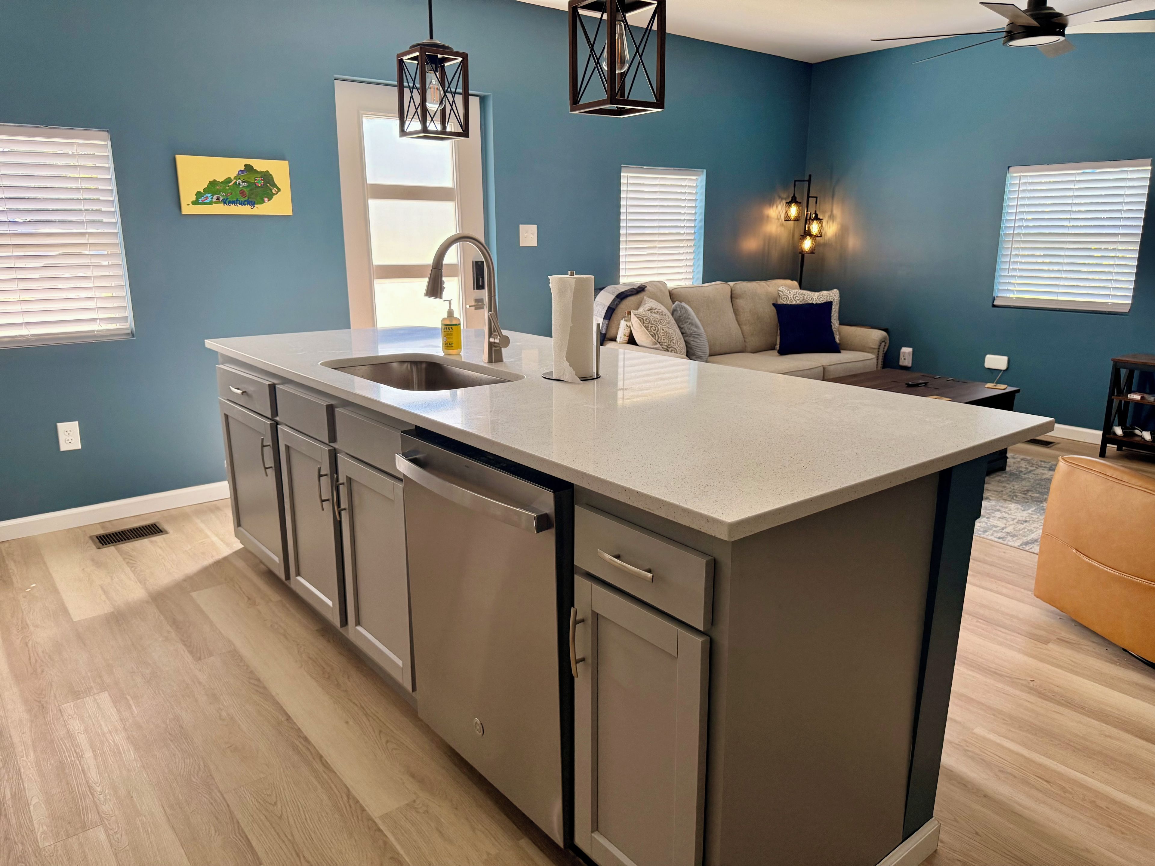 A modern kitchen with a central island, stainless steel appliances, and a blue accent wall.