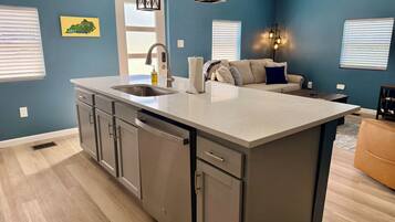 A modern kitchen with a central island, stainless steel appliances, and a blue accent wall.