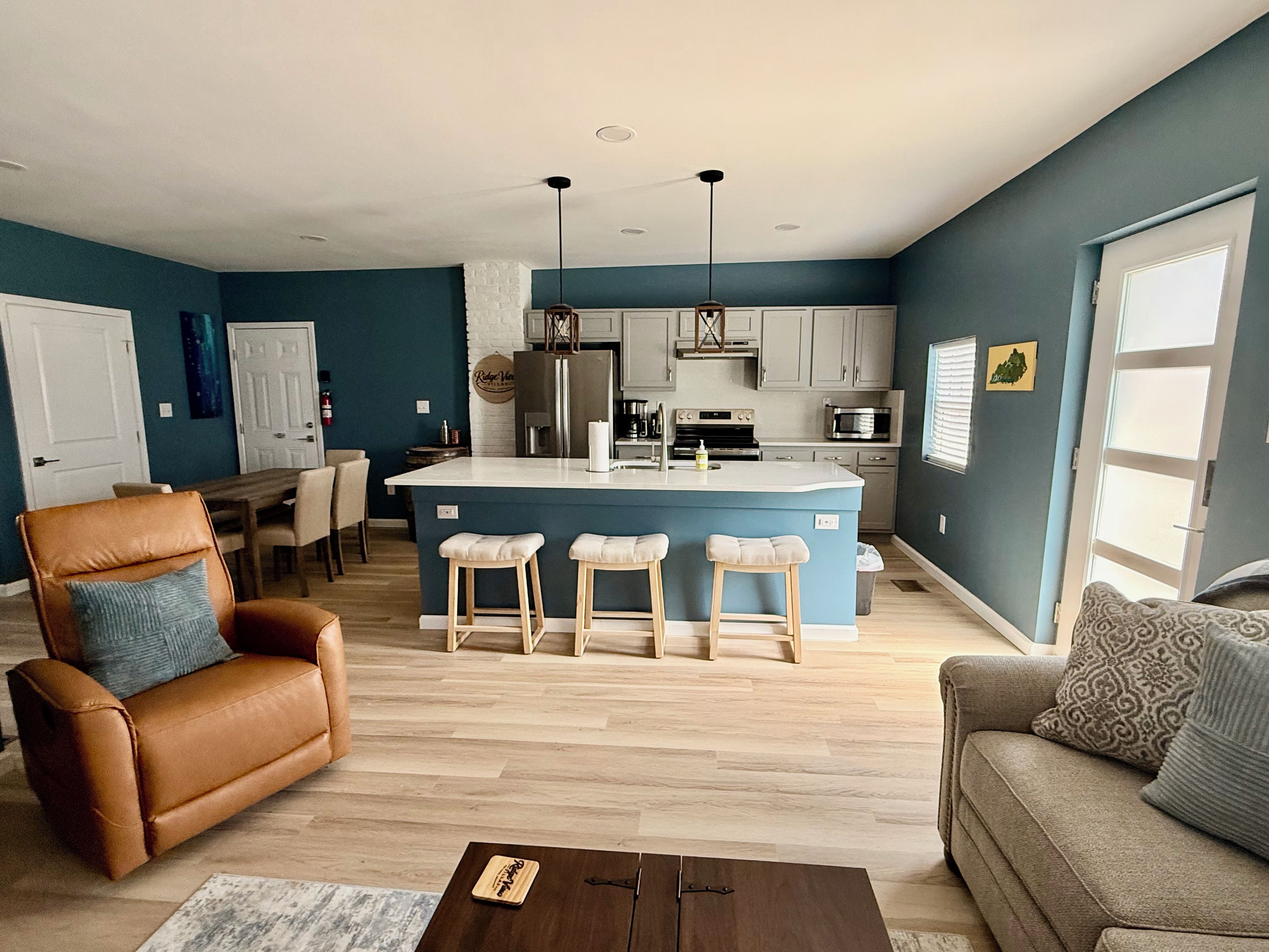 Una sala de estar moderna con un sillón de cuero marrón, un sofá gris y una mesa de centro de madera.