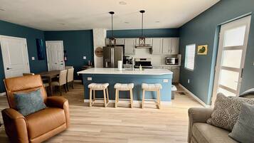 Una sala de estar moderna con un sillón de cuero marrón, un sofá gris y una mesa de centro de madera.