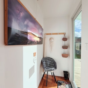 A room with a large landscape painting, a macrame wall hanging, and a patterned chair.