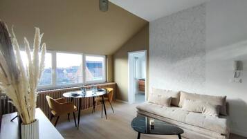 Un salon moderne comprenant un canapé, une table basse, une table à manger avec des chaises et une grande fenêtre donnant sur un paysage agréable.