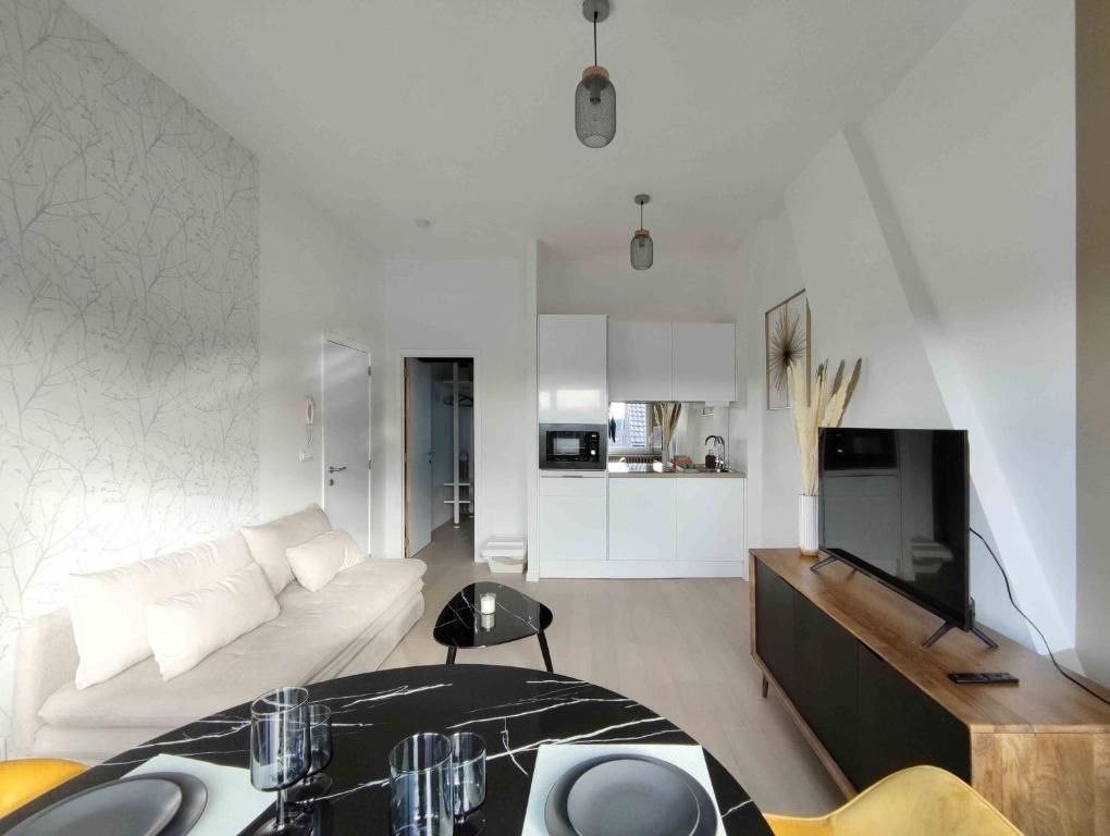 A modern living room with a dining table, sofa, and a kitchen in the background.
