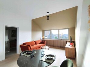 A modern living space with a dining table, a sofa, and a radiator. - L'appart by Authentic (Saint-Ghislain)
