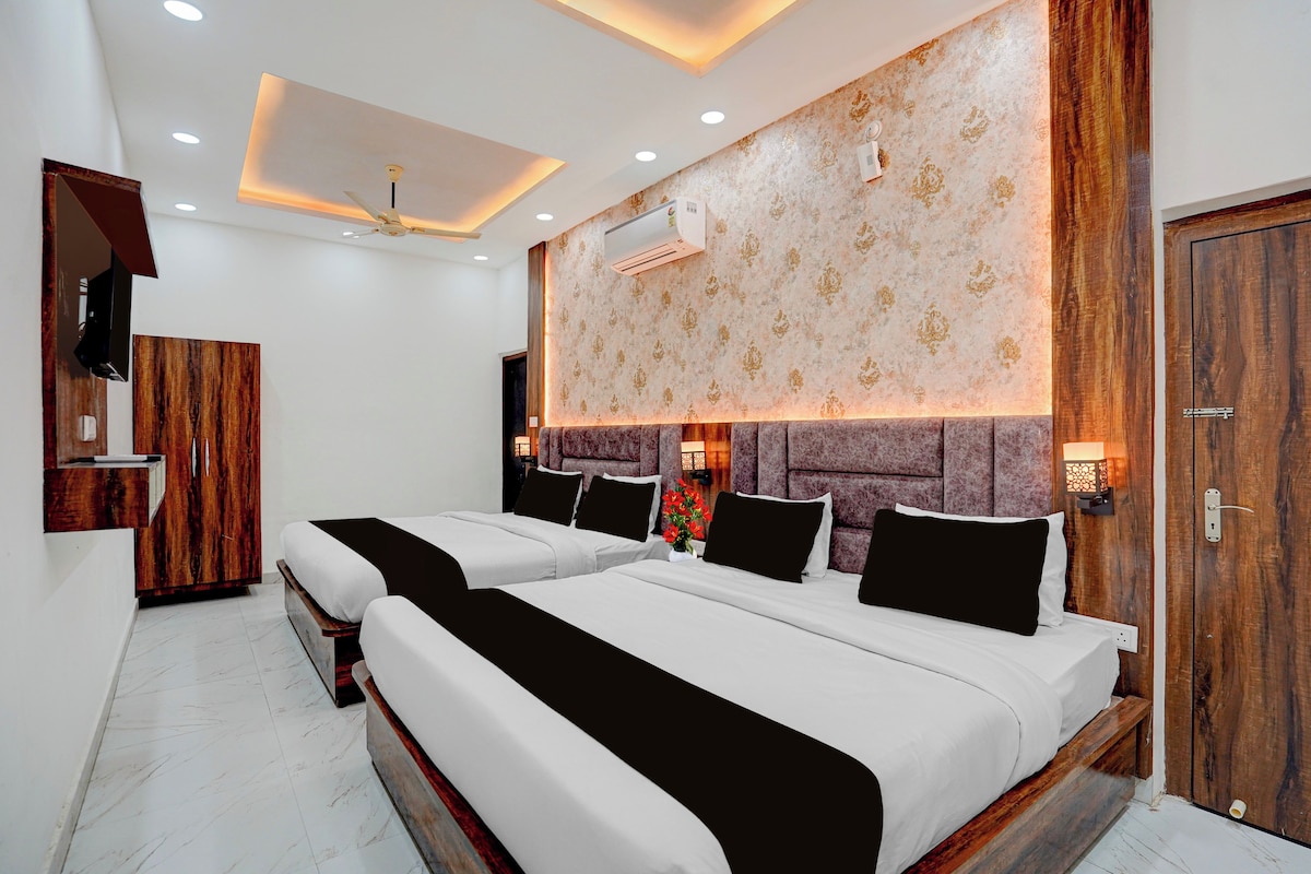 A hotel room with two beds, a wooden wardrobe, a ceiling fan, and a wall-mounted air conditioner.