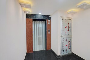 A hallway with a closed door featuring a security camera and a fire alarm. - Townhouse Oak Banaras Station (Varanasi)
