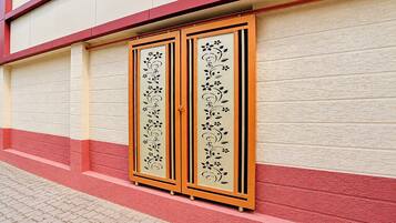 Fachada de edificio con pared texturizada en rojo y blanco, zócalo rojo y una puerta con panel decorativo.