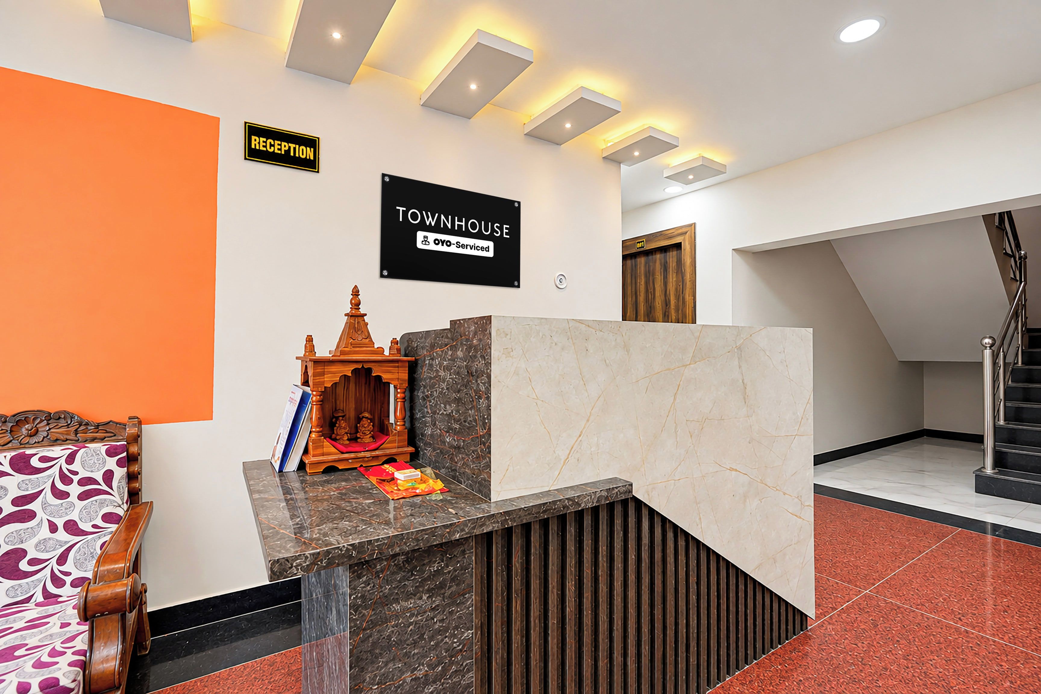 A reception desk with a sign indicating 'RECEPTION' and 'TOWNHOUSE OYO-Serviced'.