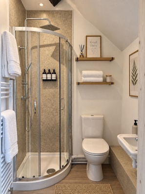 A modern bathroom with a glass-enclosed shower, a toilet, and a sink. - The Lime Kiln (Oswestry)