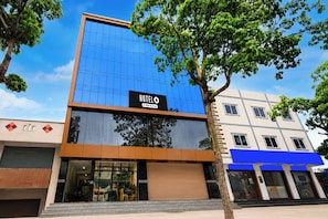 Un hotel con fachada moderna de vidrio, entrada visible y un cartel que indica que cuenta con servicios de OYO.