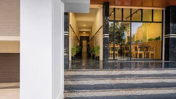 Una entrada de hotel con una escalera de mármol que conduce a un área de descanso con mesas y sillas.
