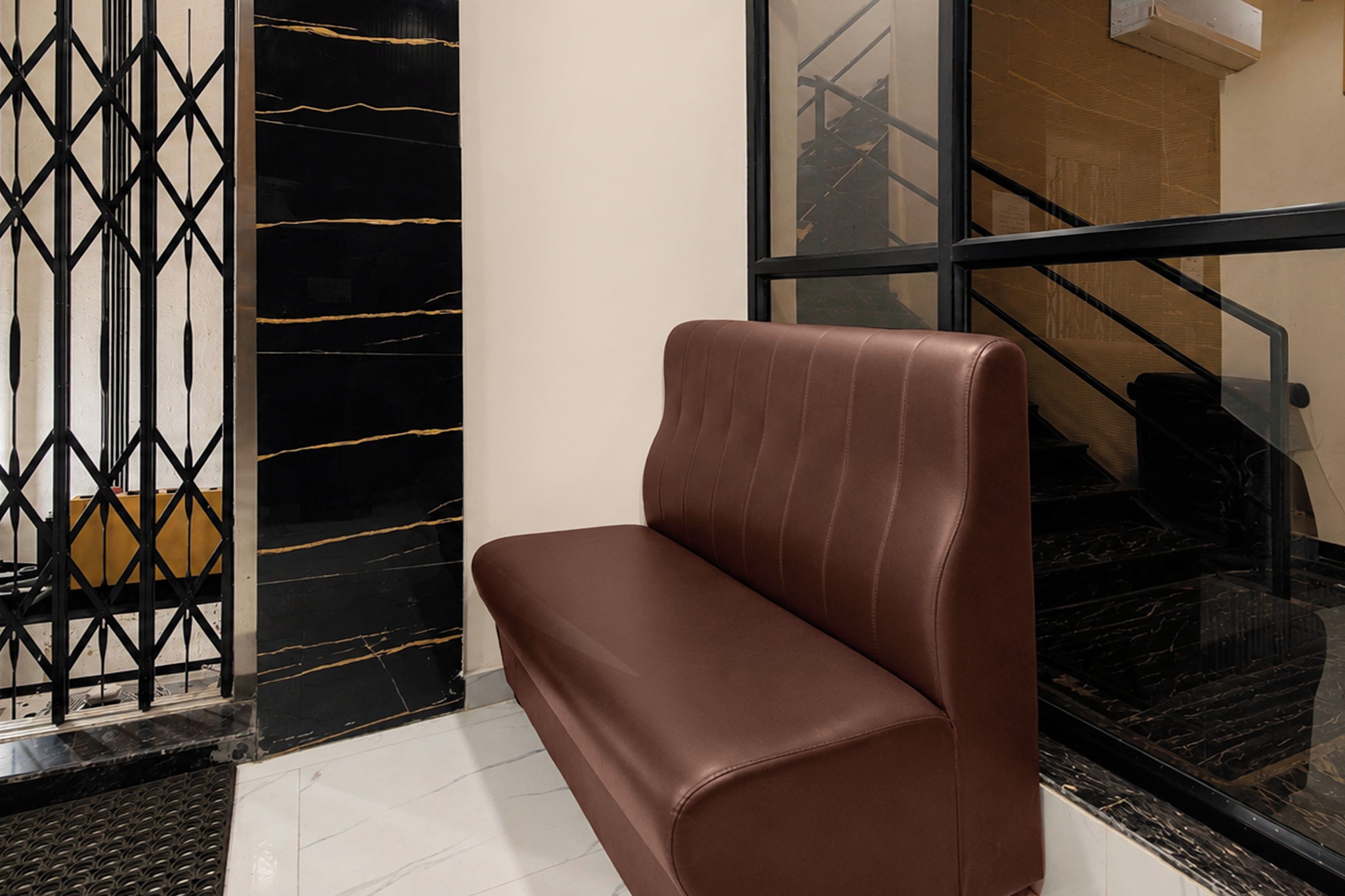 A brown leather bench in a lobby area with a glass partition and a black metal gate.