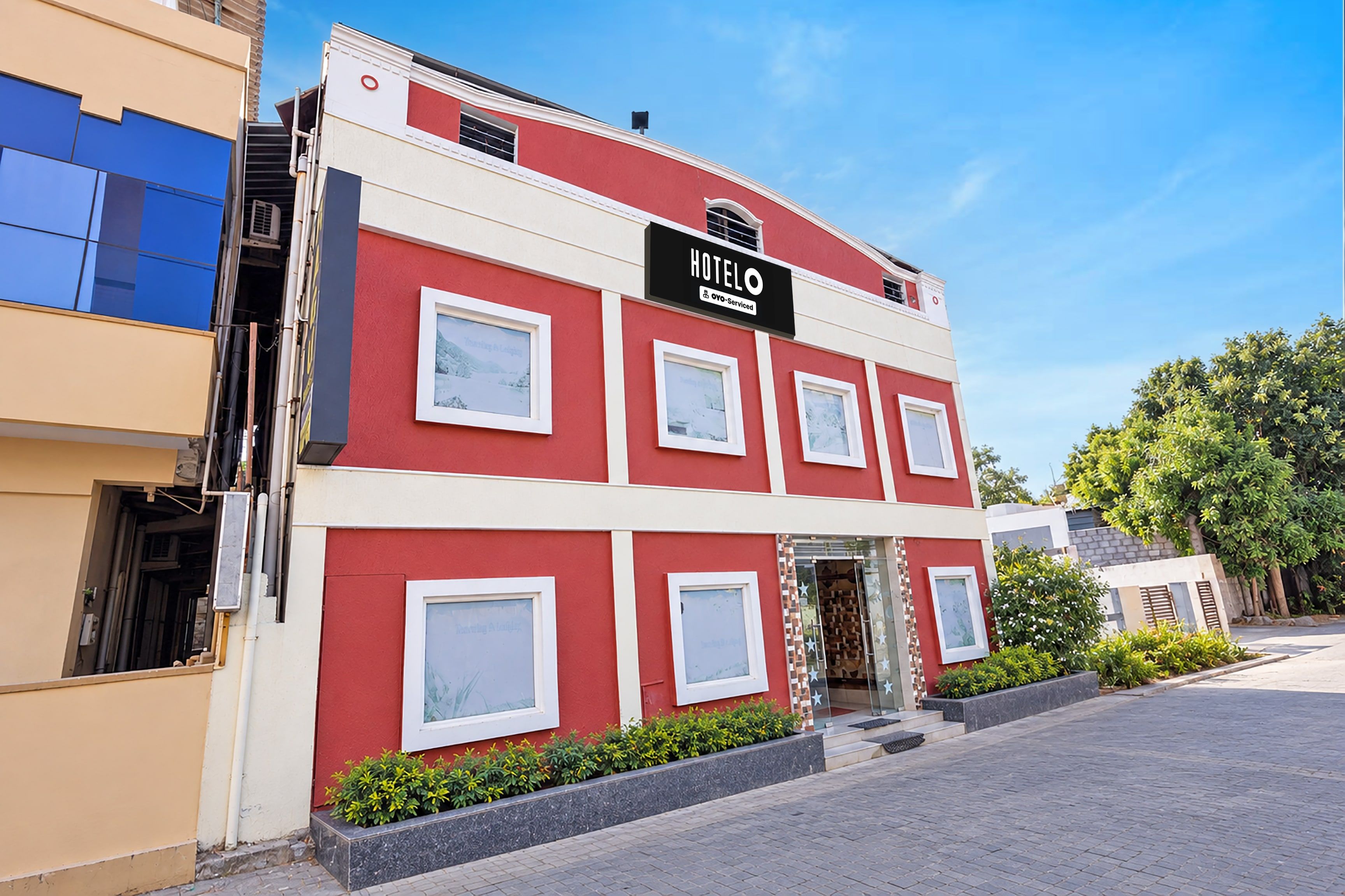 Un hotel de dos pisos con fachada roja y blanca, múltiples ventanas y un letrero que indica que es administrado por OYO.