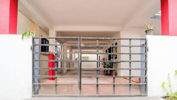 Una entrada protegida por un portón a un edificio con piso de baldosas y una pared roja en un lateral.