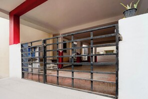 A gated entrance with a metal gate, a red pillar, and a potted plant on the right. - Hotel O Coimbatore International Airport (Coimbatore)