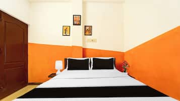 Una habitación de hotel con una cama, una mesita de noche, una lámpara y una pared con tres cuadros enmarcados.