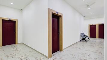 A corridor with marble flooring, wooden doors, and a ceiling fan.