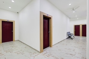 Un pasillo con suelo de mármol, puertas de madera y un ventilador de techo.