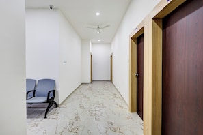Um corredor com ventoinha no teto, um banco e uma porta.