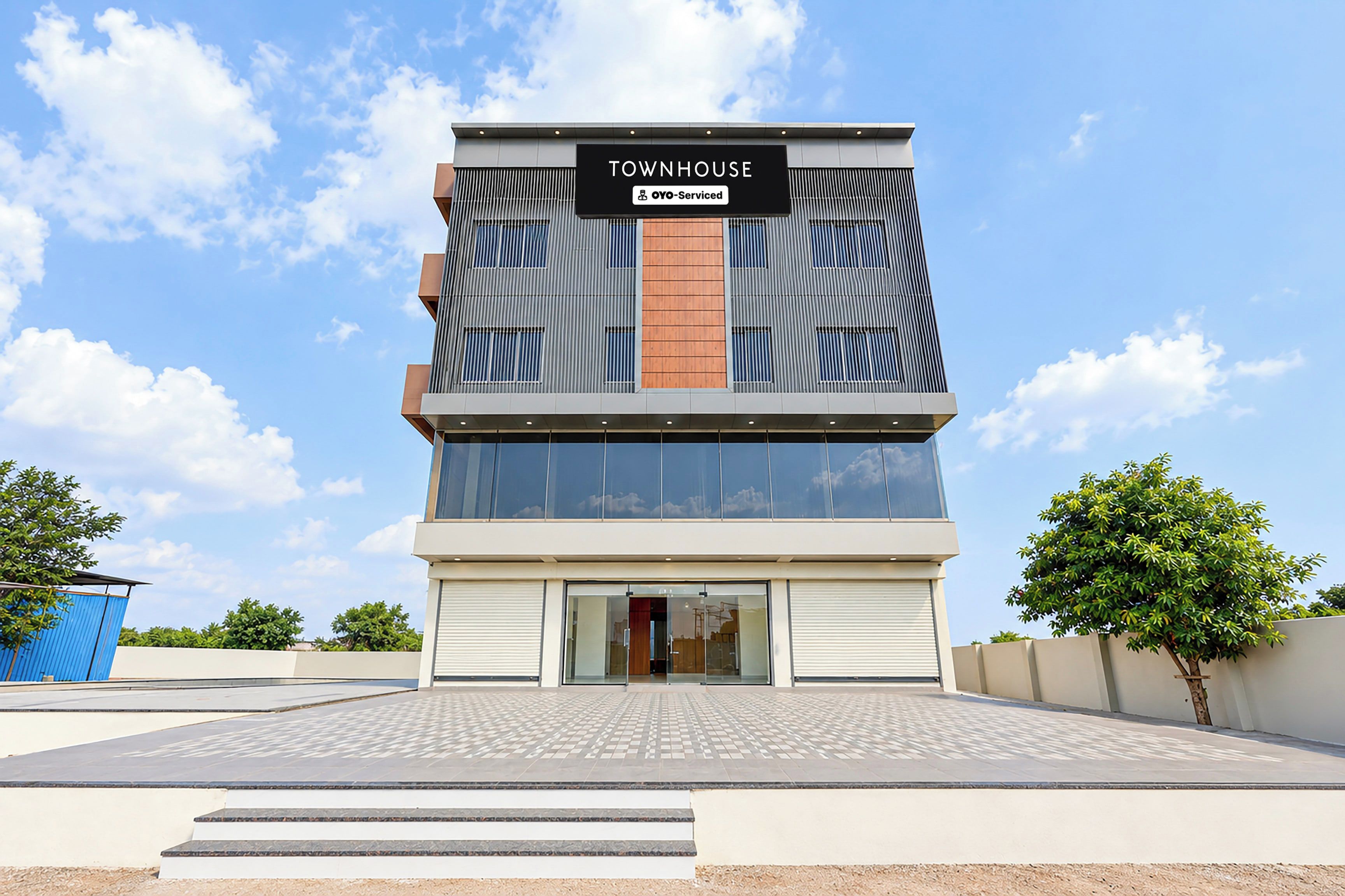 Un edificio moderno con un letrero que dice 'TOWNHOUSE' y 'oyO-Serviced', indicando un apartamento con servicios.
