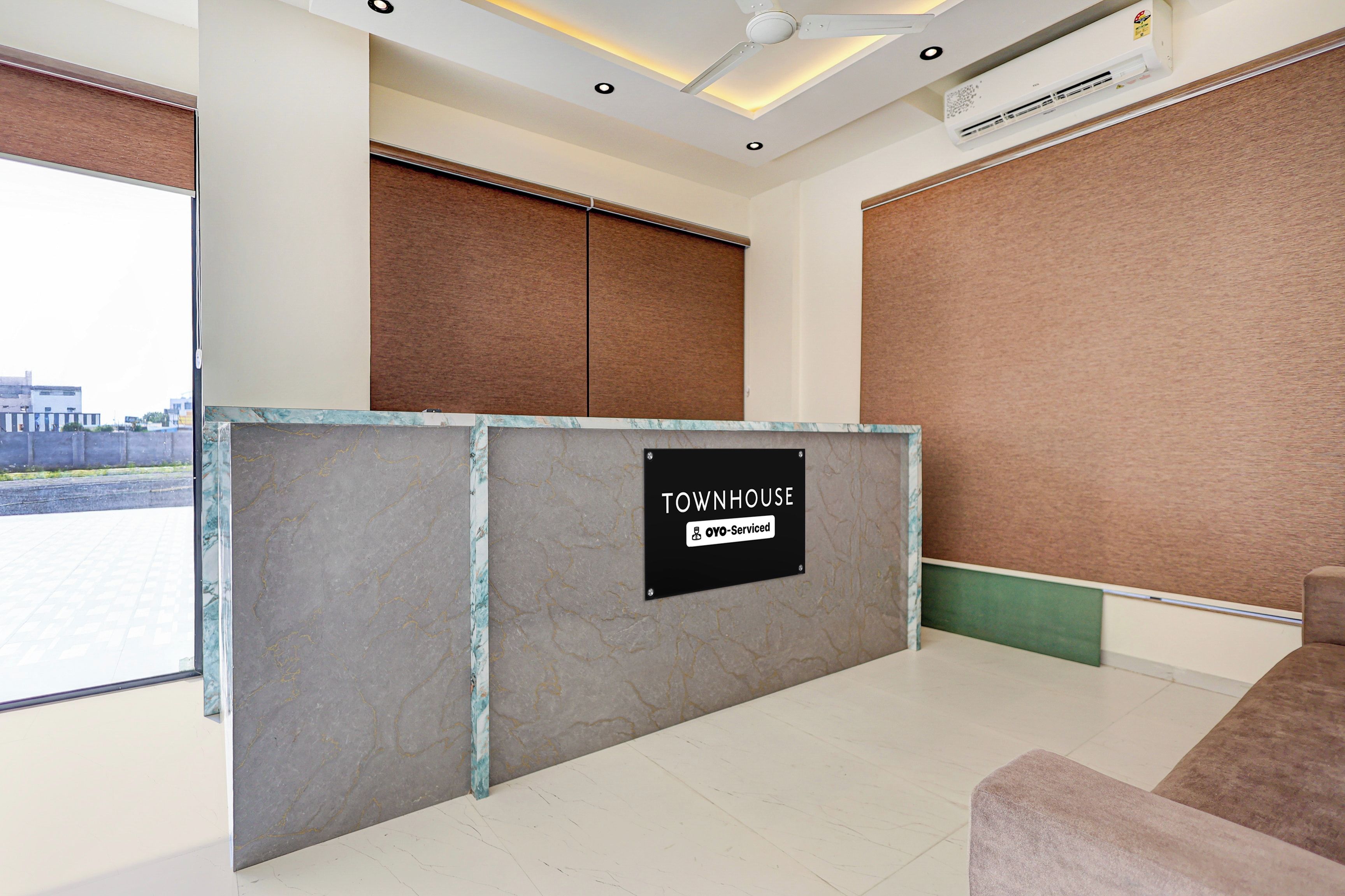 A reception area with a marble counter, a sign indicating it is serviced by OYO, and a view of the outside.