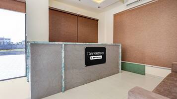 A reception area with a marble counter, a sign indicating it is serviced by OYO, and a view of the outside.