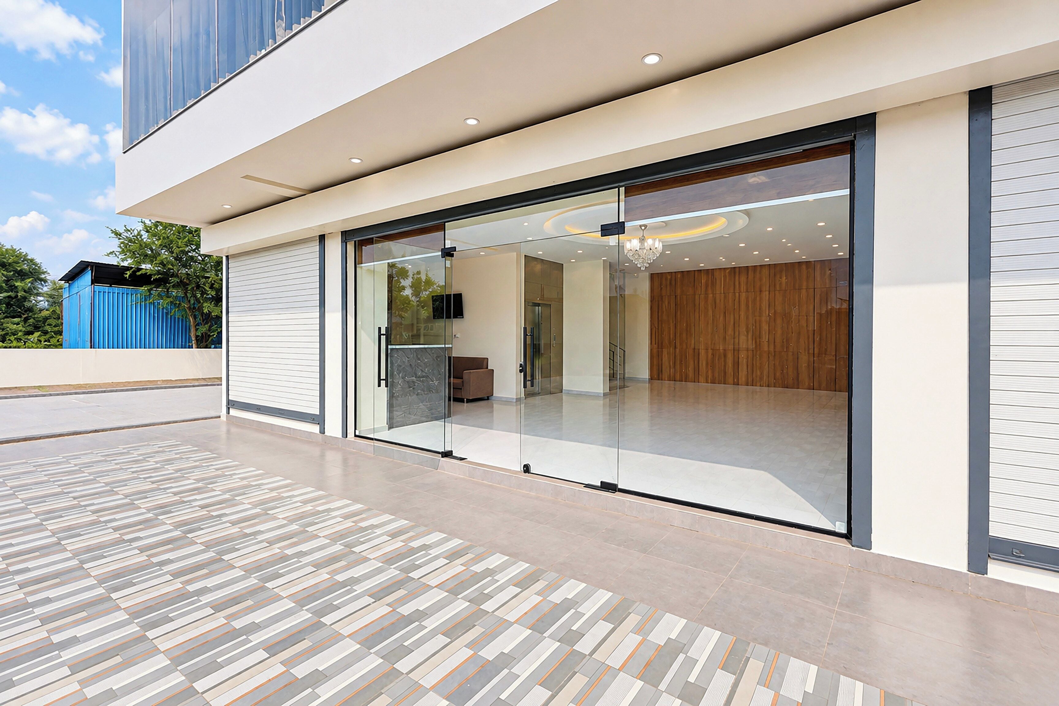 Een modern gebouw met een glazen ingang, een vloer met een patroon en uitzicht op het interieur.