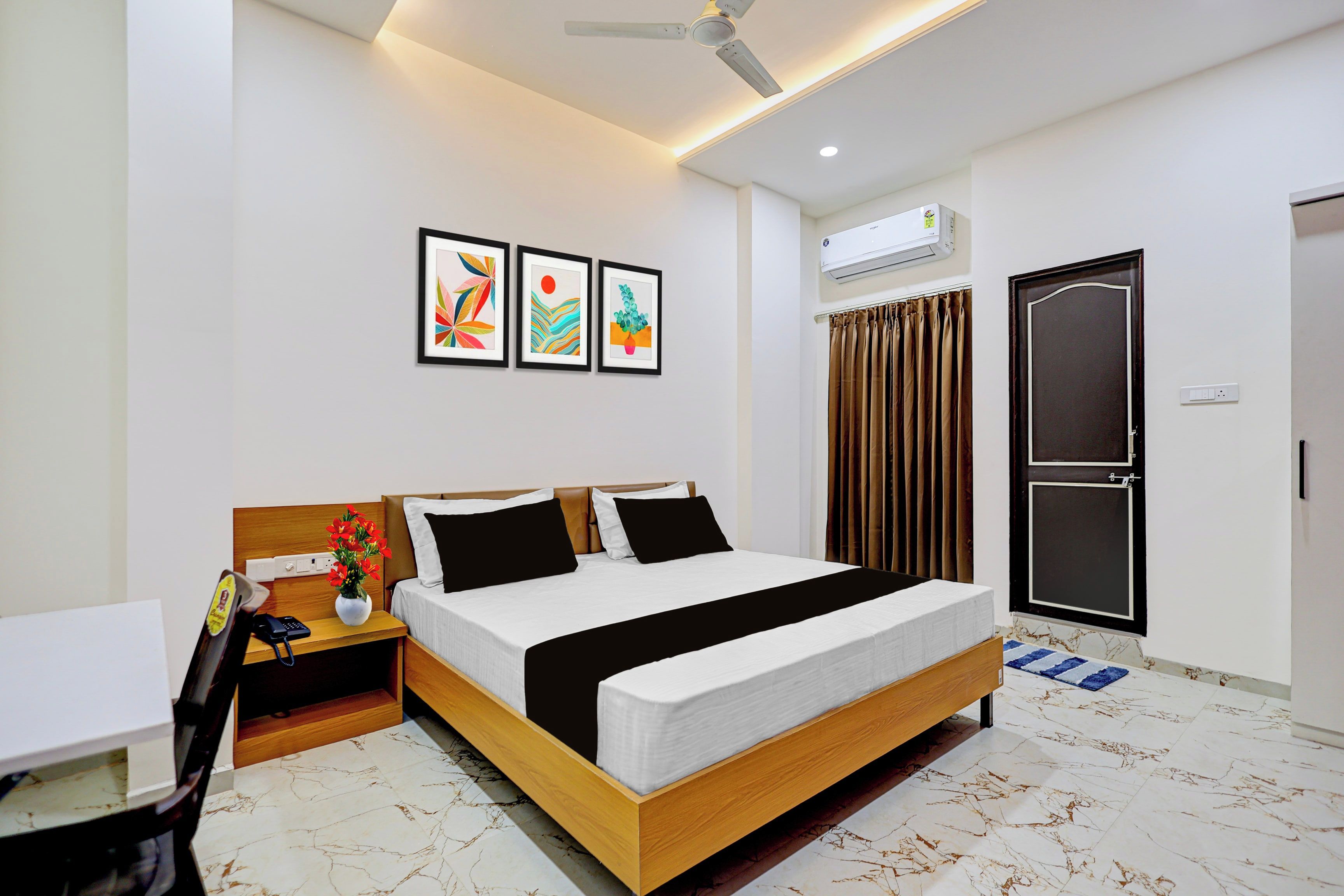 A modern hotel room with a bed, bedside table, and a small desk.