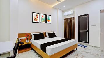 A modern hotel room with a bed, bedside table, and a small desk.