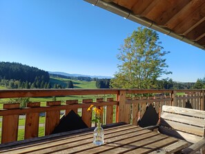 Una terraza de madera con vistas despejadas a un paisaje verde y montañas lejanas.